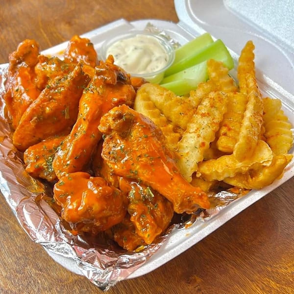 Sauce Wing Co. buffalo wings with crinkle-cut fries, celery sticks, and ranch in a to-go container.