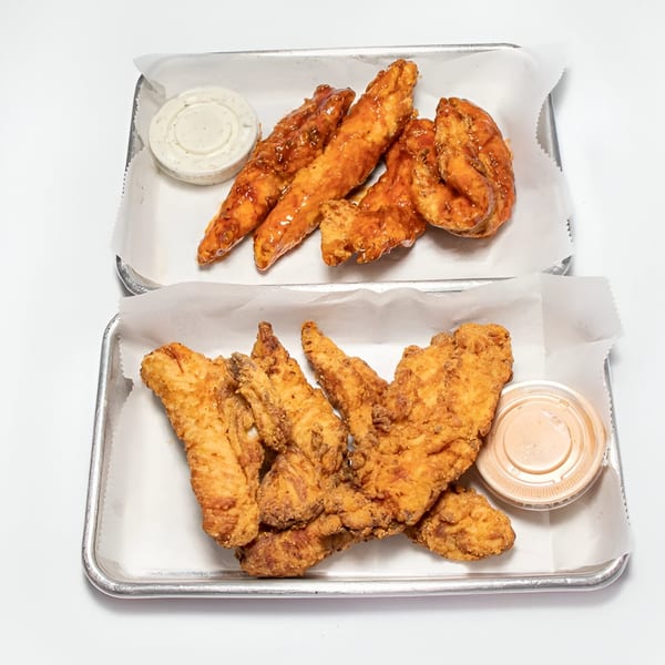 Two trays of Sauce Wing Co. wings, one with sauced wings and the other with crispy fried wings.
